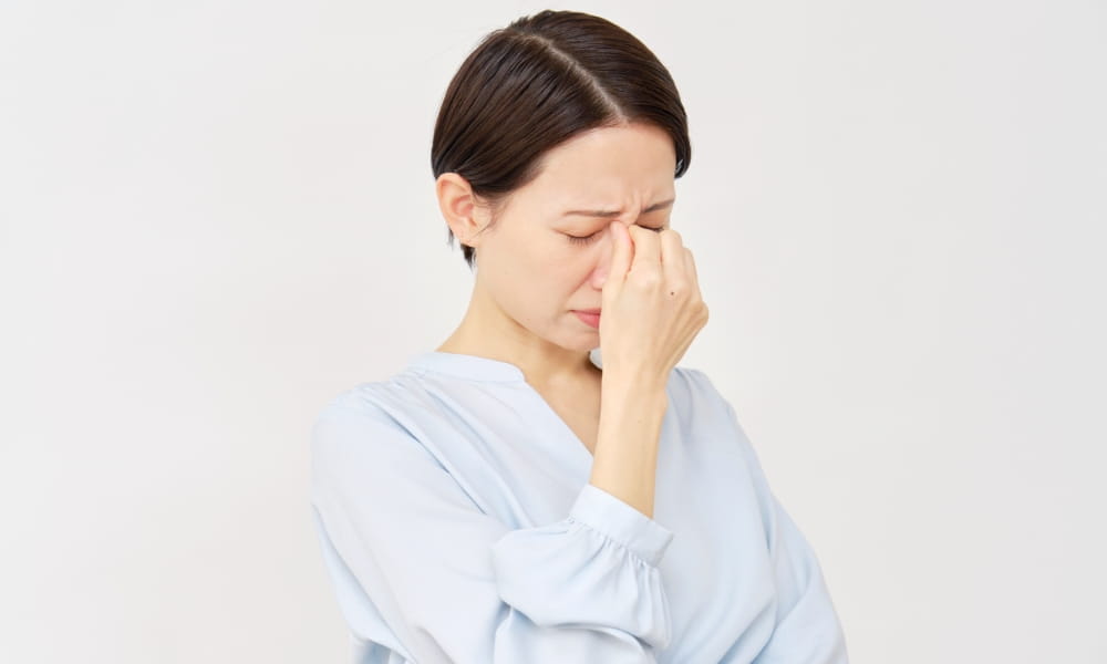 眼精疲労で目に手を当てる女性